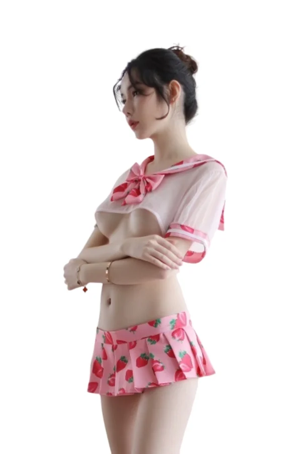 OEM Naughty School Girl Costume Side Pose in Pink Strawberry Outfit - Supreme Lingerie A model in an OEM naughty school girl costume posing sideways, featuring a sheer pink sailor top with a bow and pleated strawberry mini skirt.